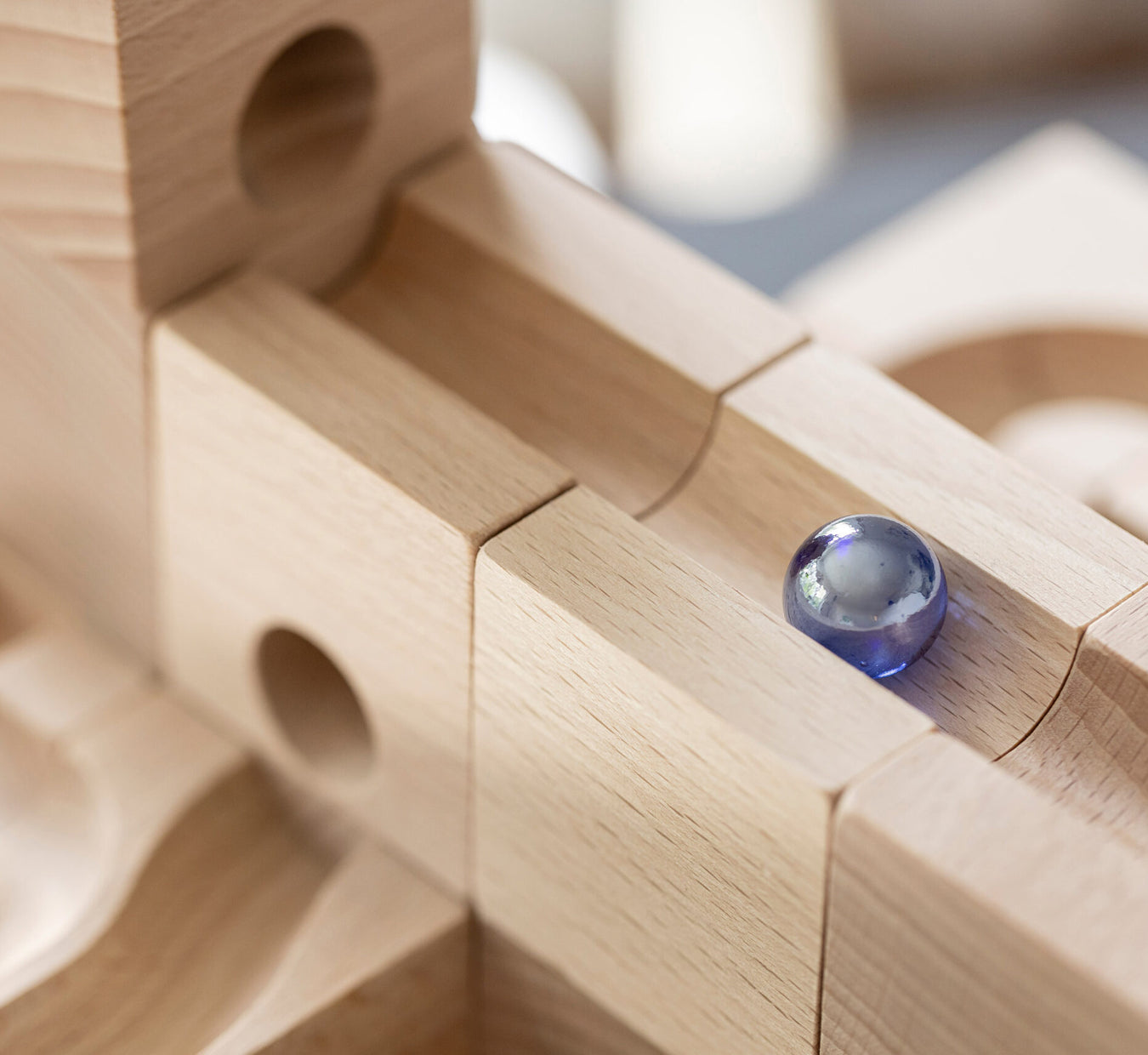 Wooden blocks with smooth channels cut for marbles to pass thought, blue marble runs down a ramp