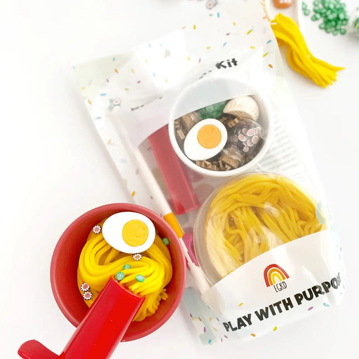 Play dough kit including a Melamine bowl, noodle extruder, chopsticks with chopstick trainer, dumpling charm, egg charm, chili sauce charm, green onion fimo, and fish cake fimo.