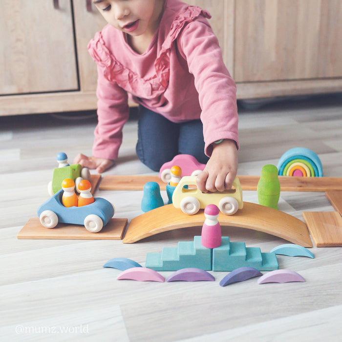A. young girl playing with grimms wooden toys in a smallworld play scene
